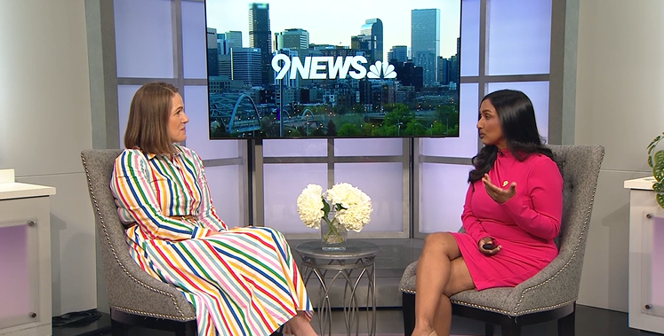 image of two women, both wearing dresses, sitting down across from one another for an interview