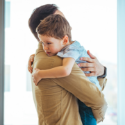 man holding small child with short brown hair in front of a bright window