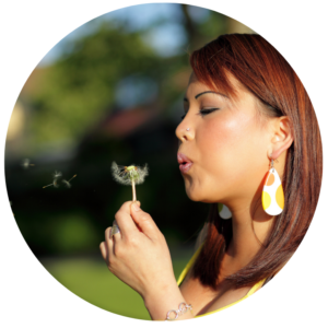 young woman blowing dandelion
